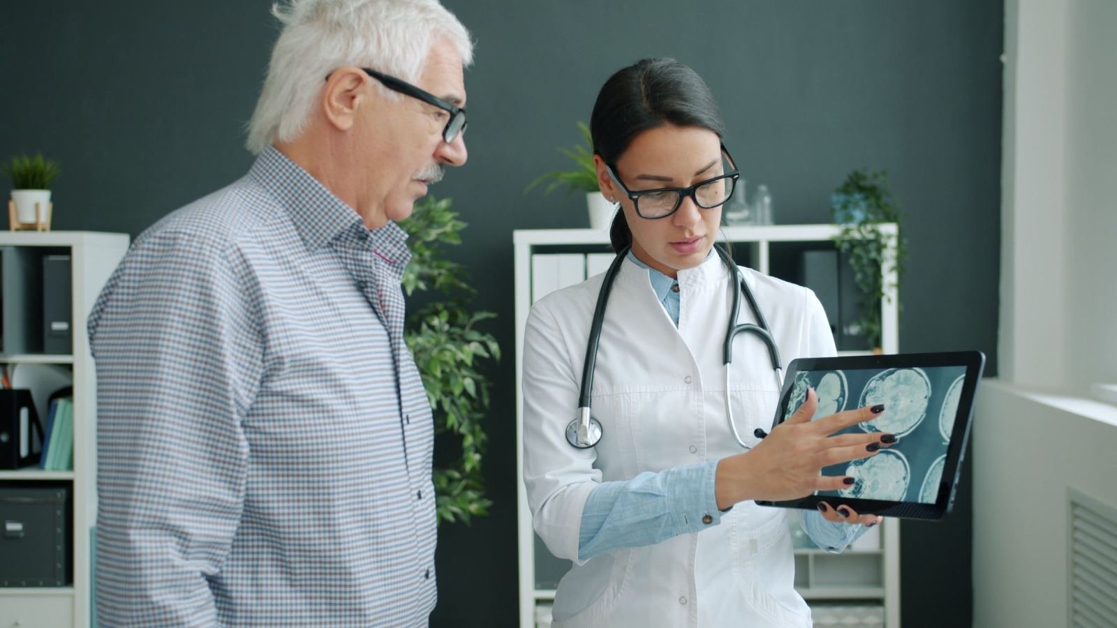 A doctor shows brain scan images on a tablet to an older man