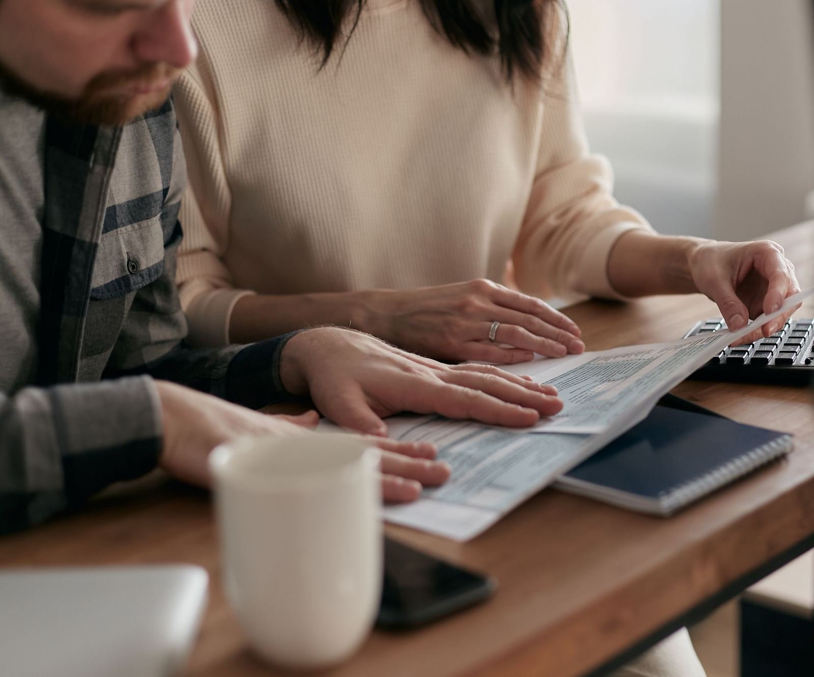 A man and woman review paperwork together at a wooden table