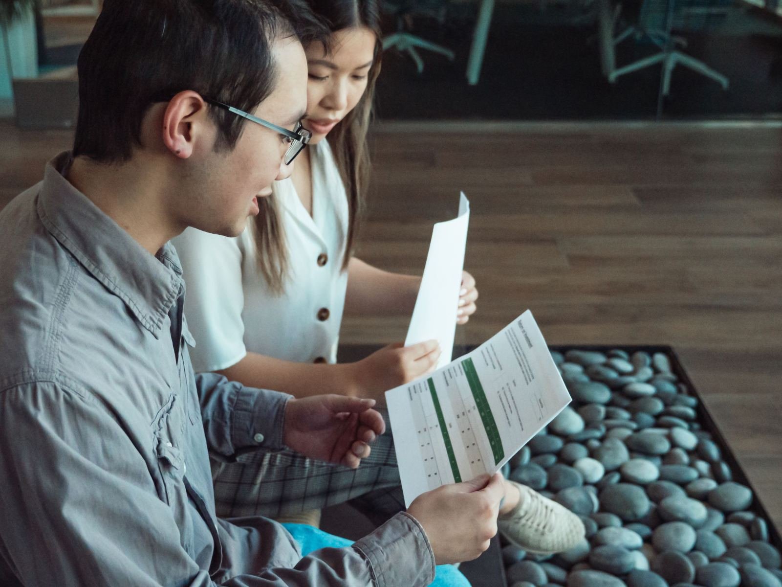 A man and woman review printed documents together in a bright office