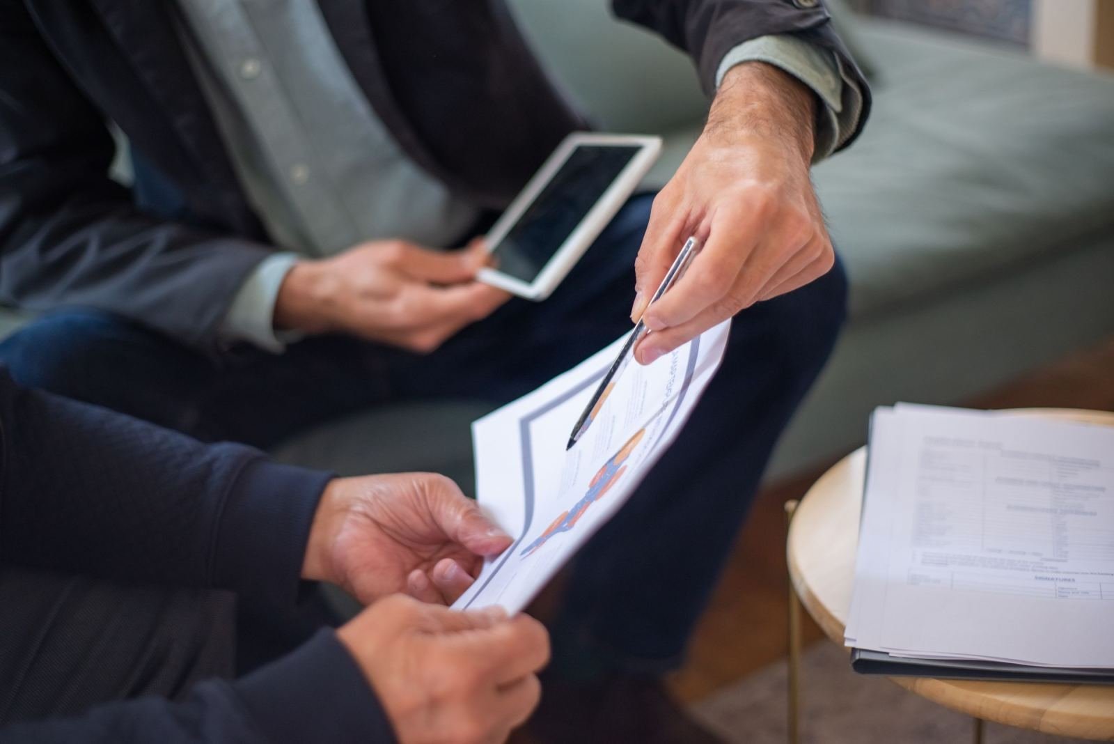 A pair of people look at a chart on paper while holding a tablet.
