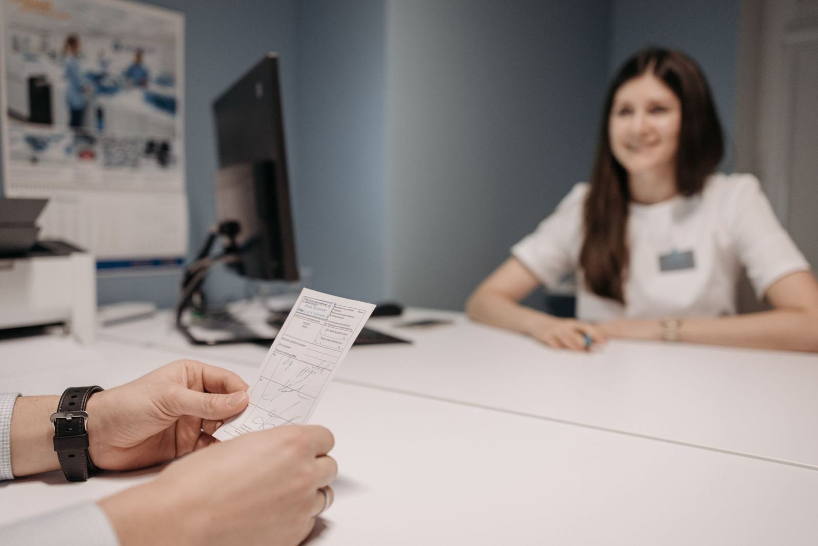 A clinician in a white shirt smiles at a person holding a printed care document