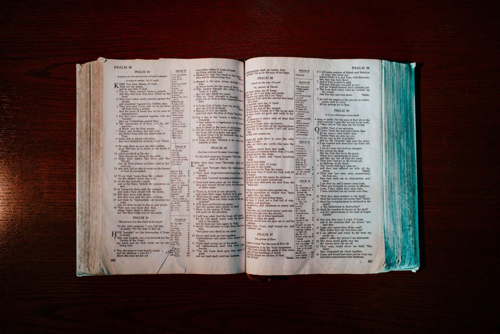 An open Bible with worn pages resting on a dark wooden surface