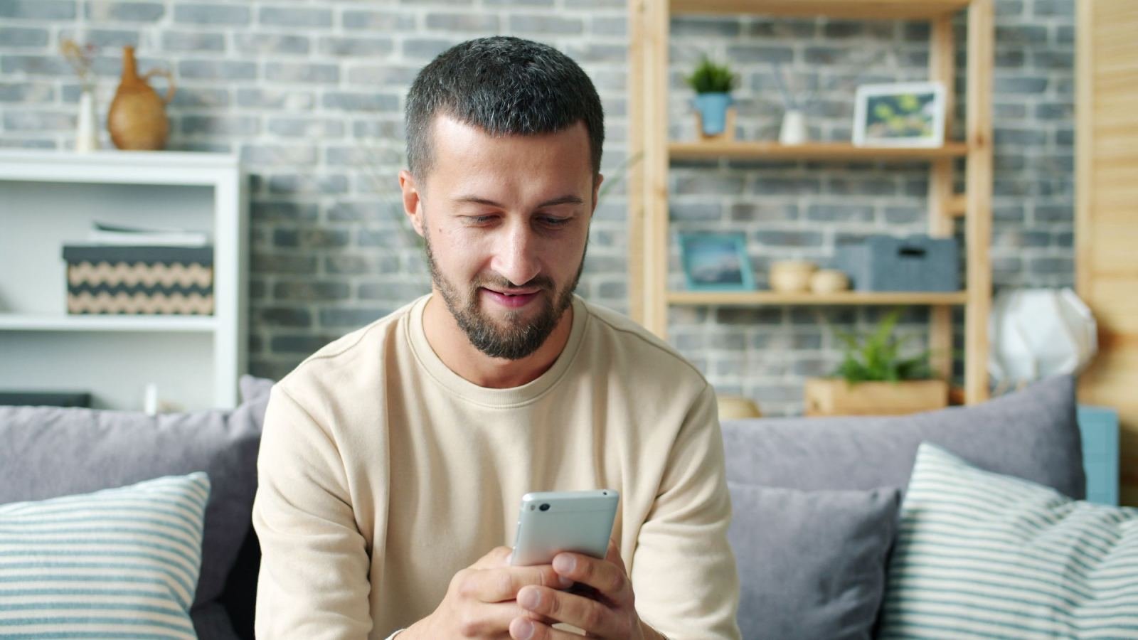 A man sitting on a sofa looks at his smartphone