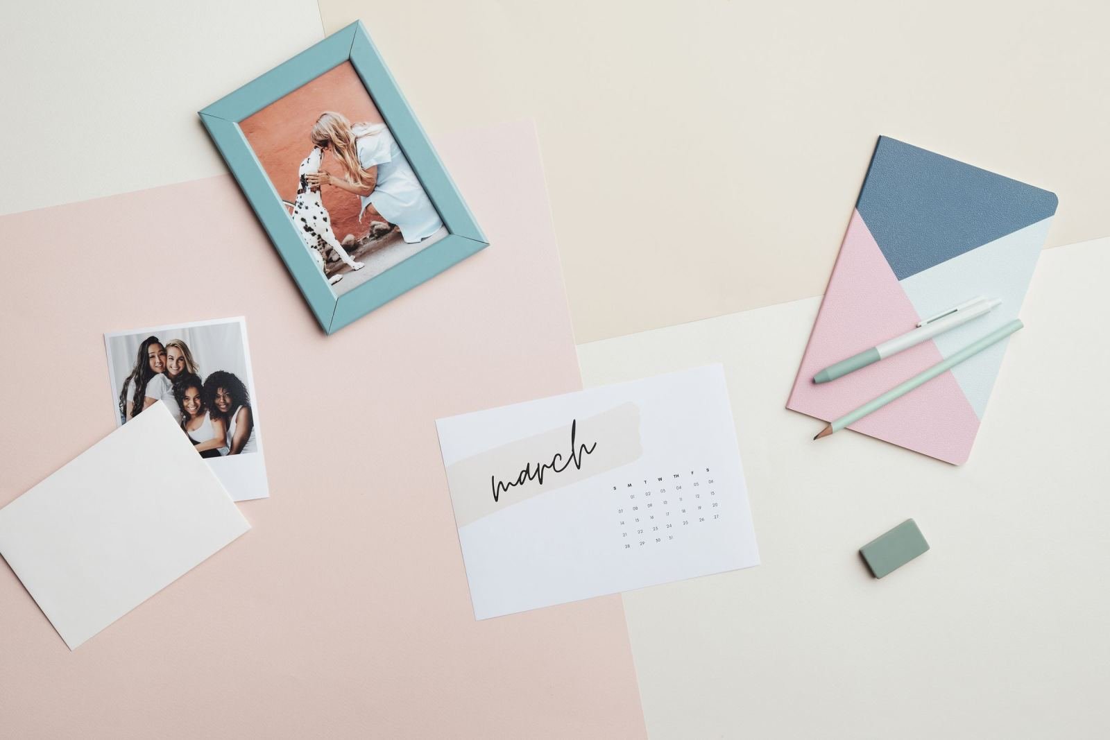 A calendar for March, framed photos, and a notebook on a light surface