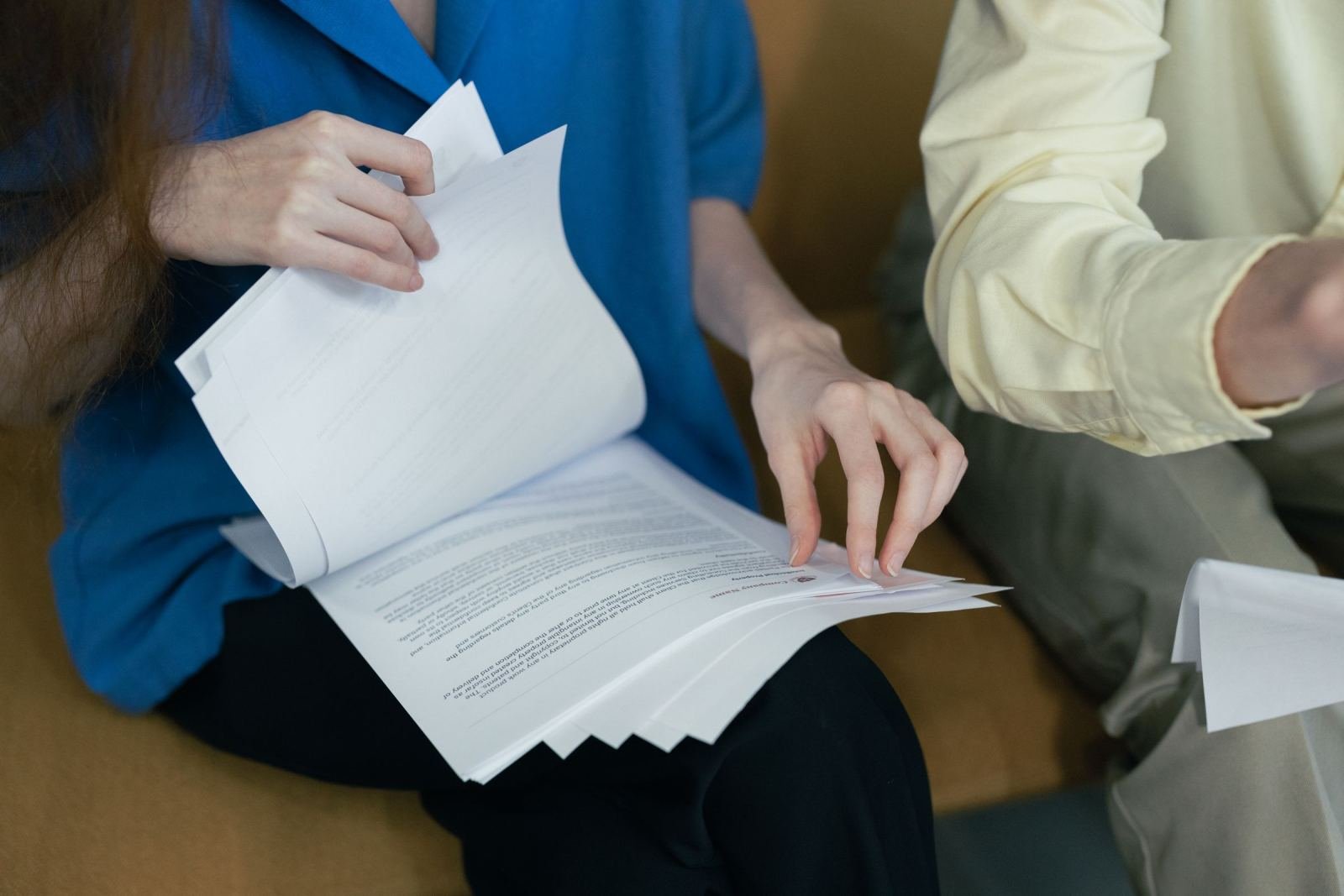 Two people sit side by side looking over papers.