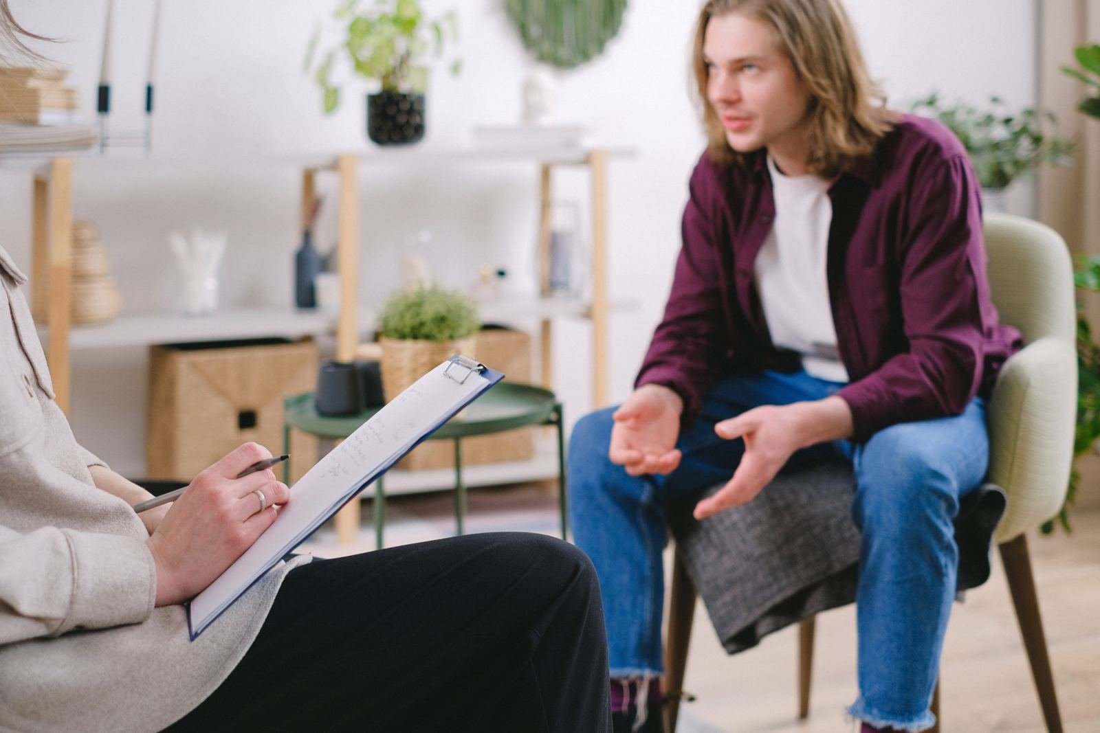 A counselor with a clipboard listens to a man in a purple shirt