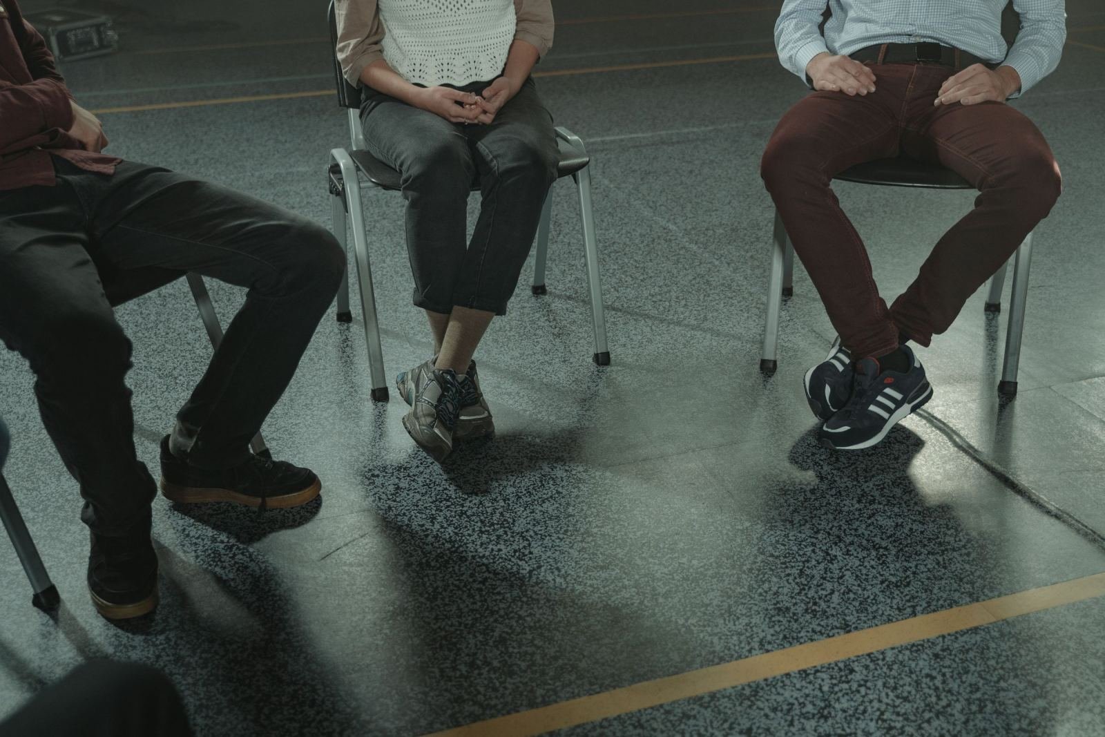 Three people sitting in a circle of chairs in a large room