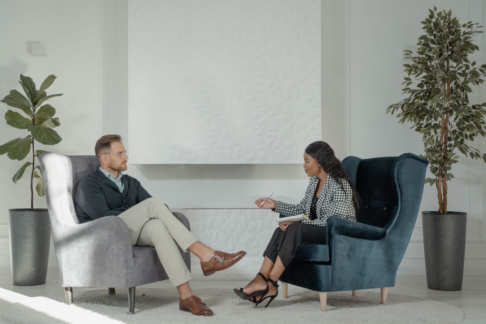 A man and a woman chat while holding a notebook in a bright, modern office.