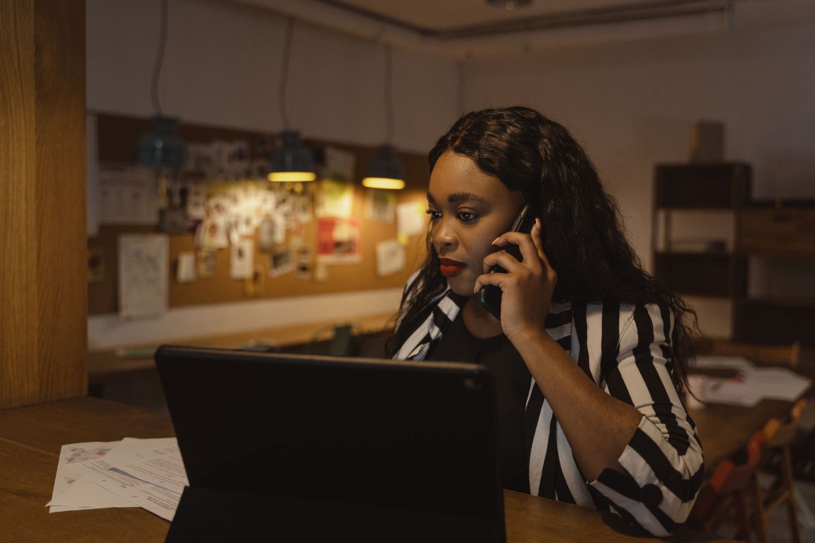 A woman sits at a desk, looking at her laptop while on a call.