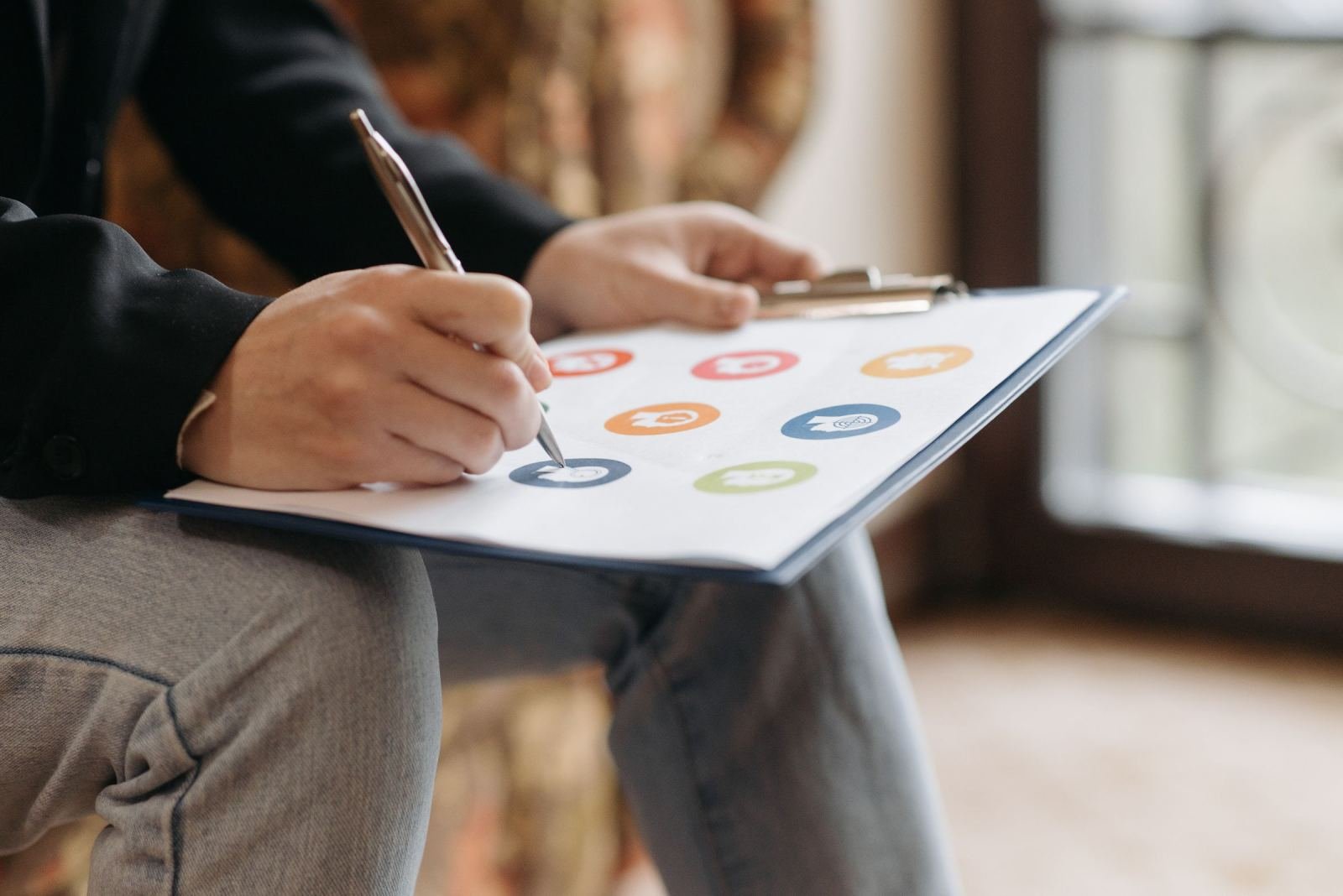 A hand holds a pen above a board filled with bright symbols.