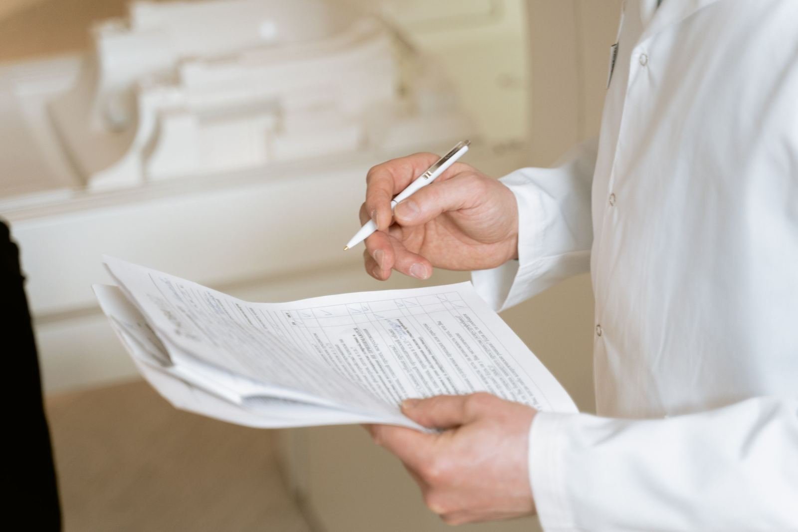 A doctor in a white coat looks over forms with a patient.