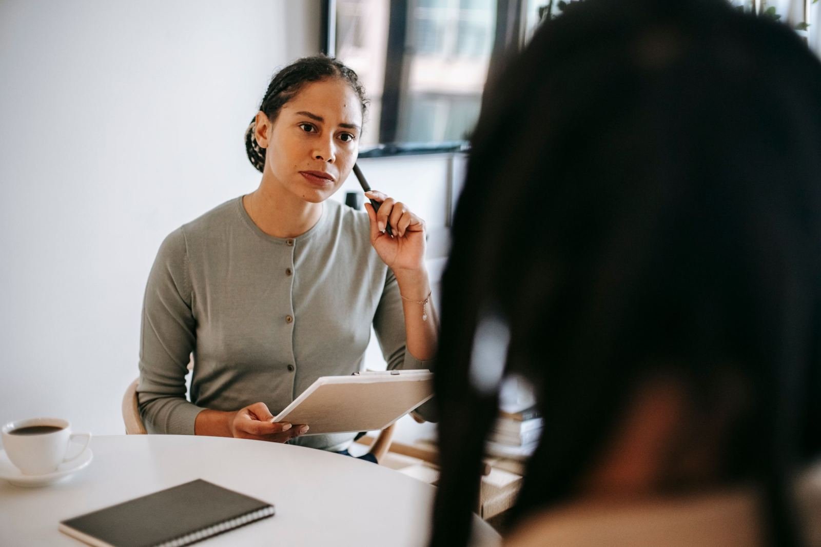 A professional woman with a notebook listens to a client in a bright office