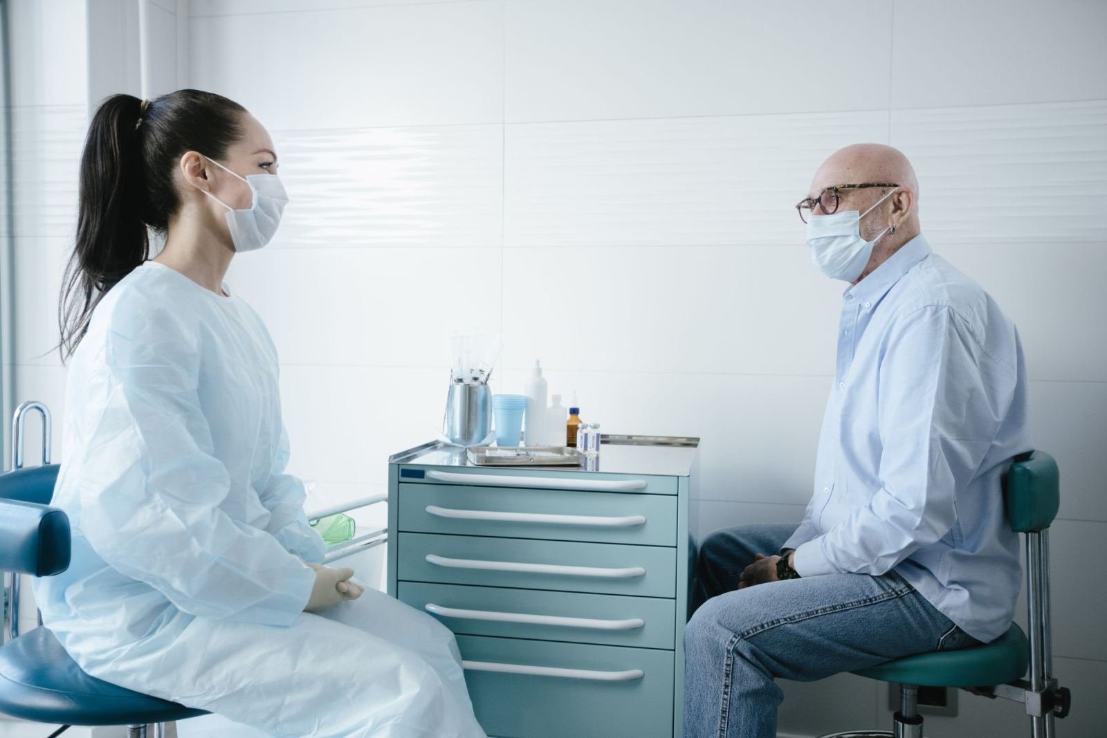 A doctor and a patient, both in face masks, look at one another.