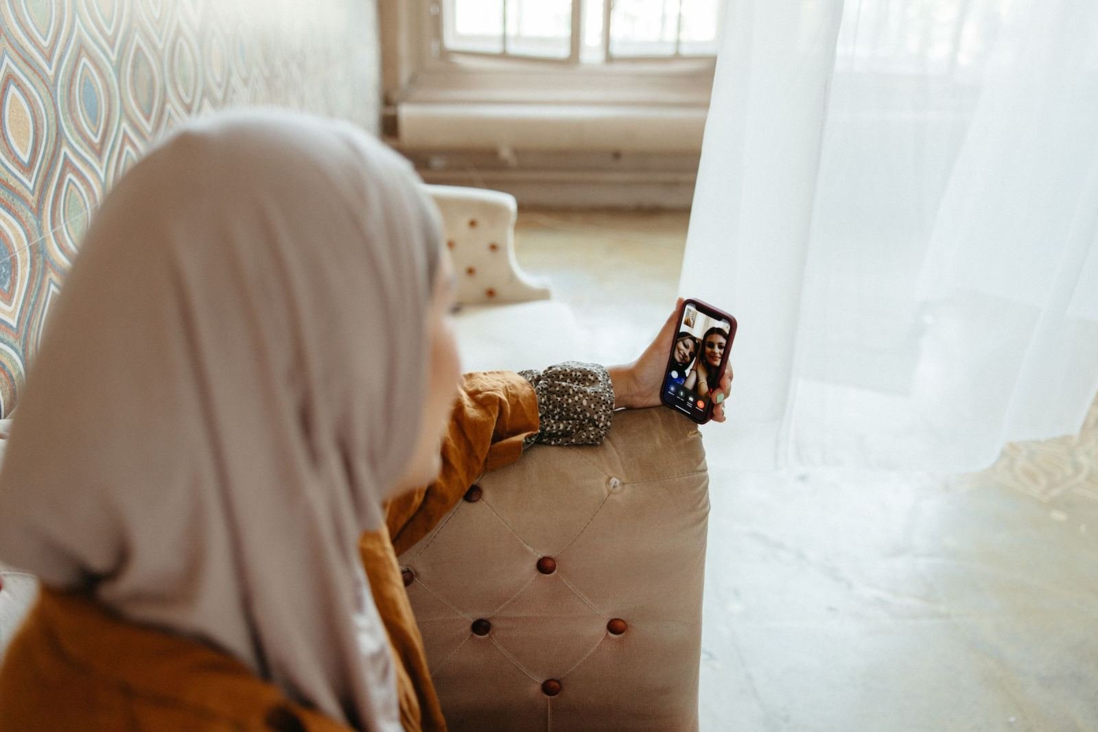 A woman in a hijab looks at her phone on a video call