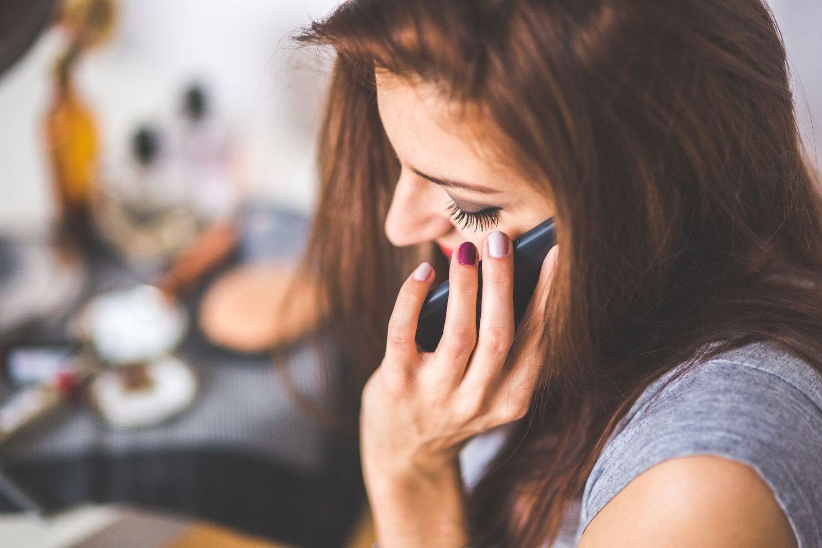 A woman with long brown hair talks on a smartphone and smiles