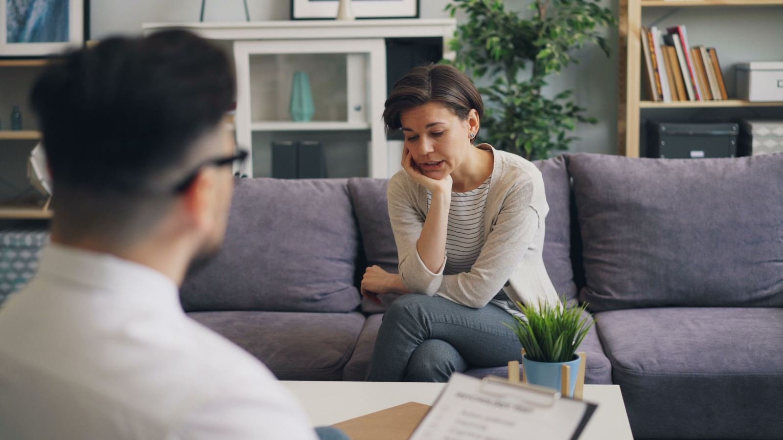 In a calm room, a clinician chats with a woman sitting on a couch.