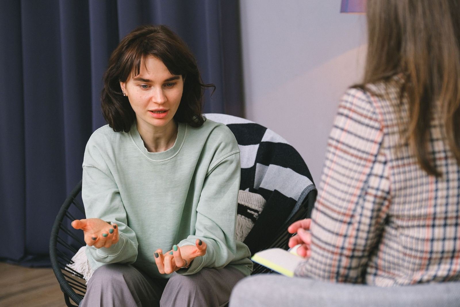 A woman uses hand signals as she talks with a counselor in a well-lit room