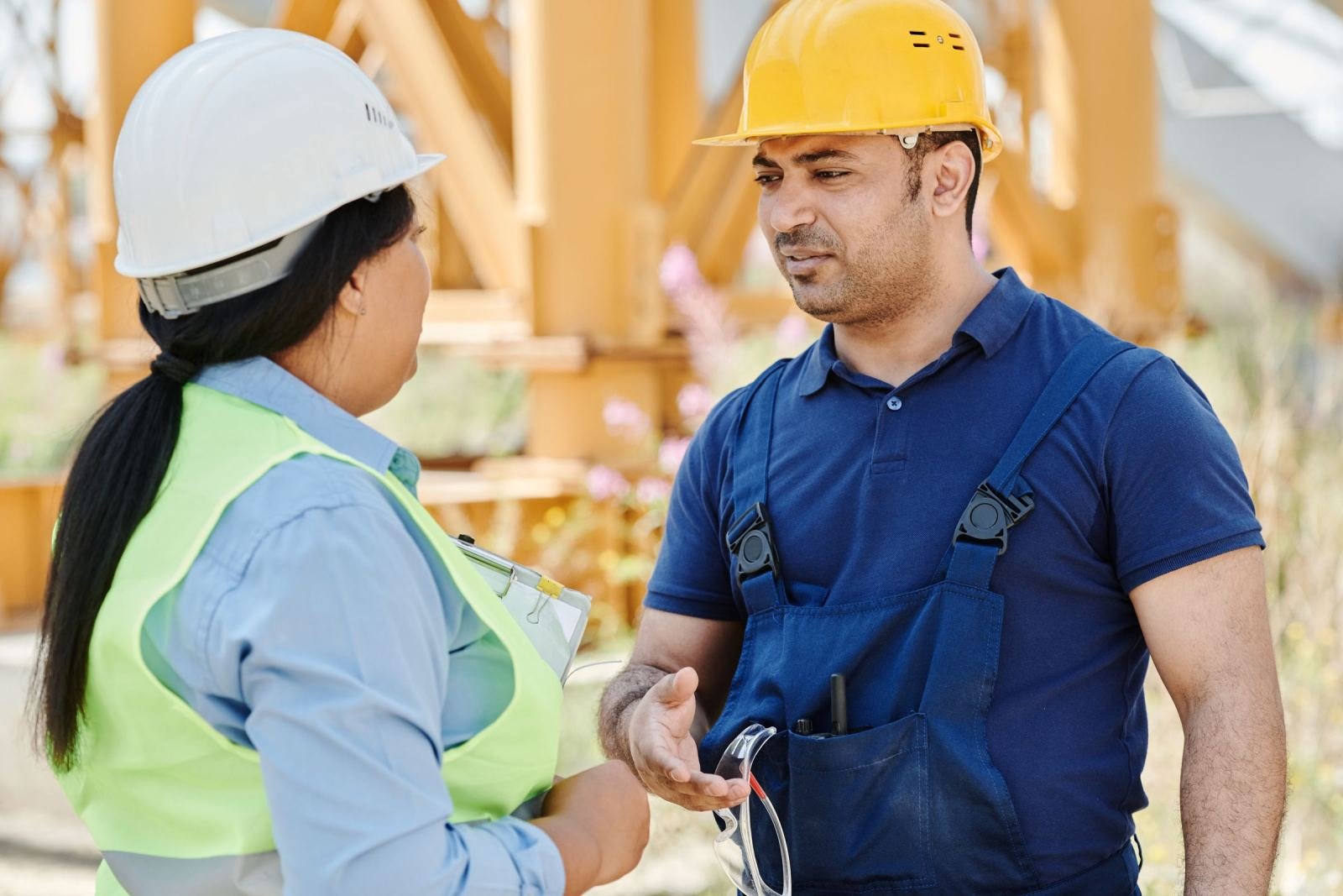 Two building crew members in safety gear chatting outside