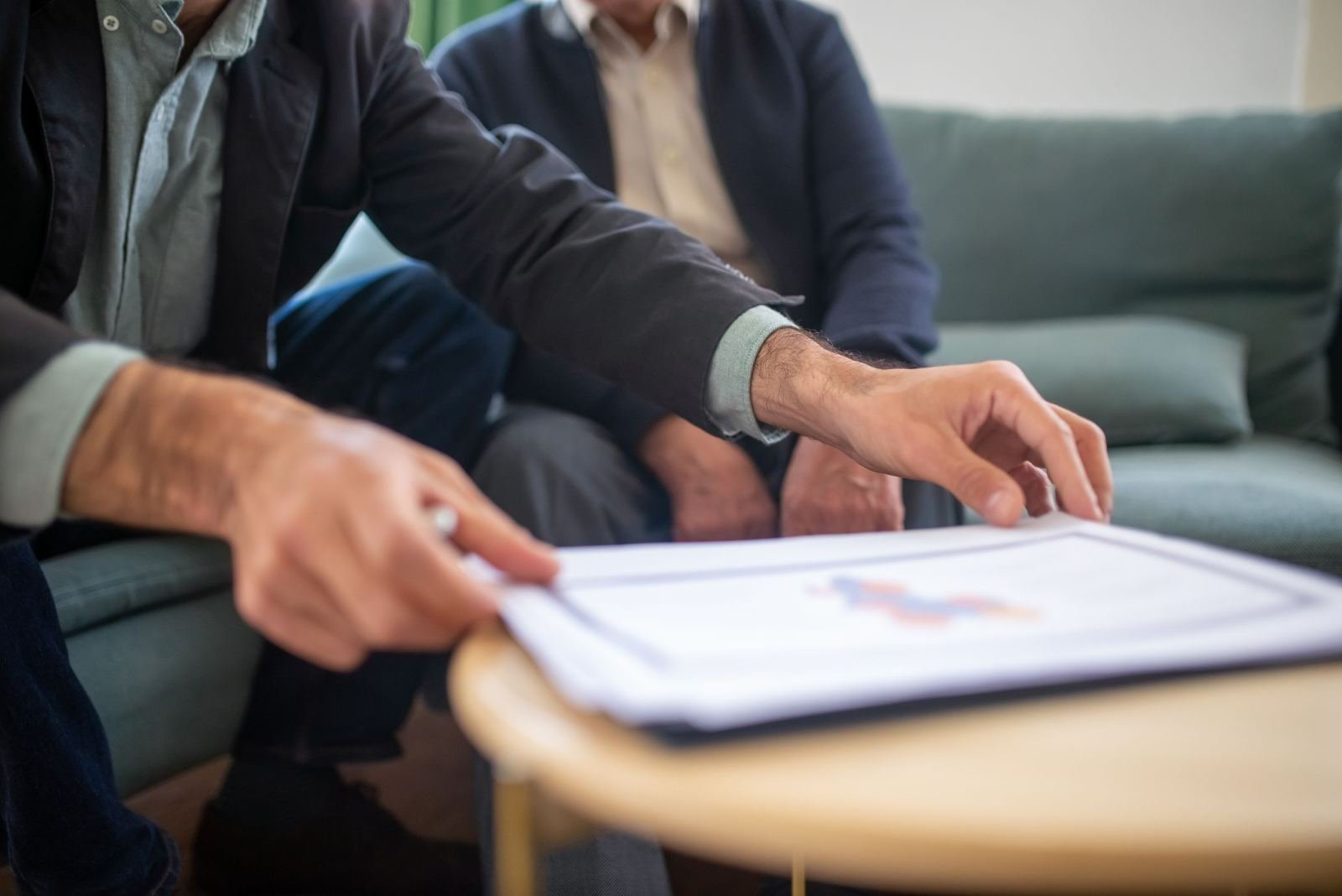 Two professionals in business wear look over a paper with a graph on a desk.