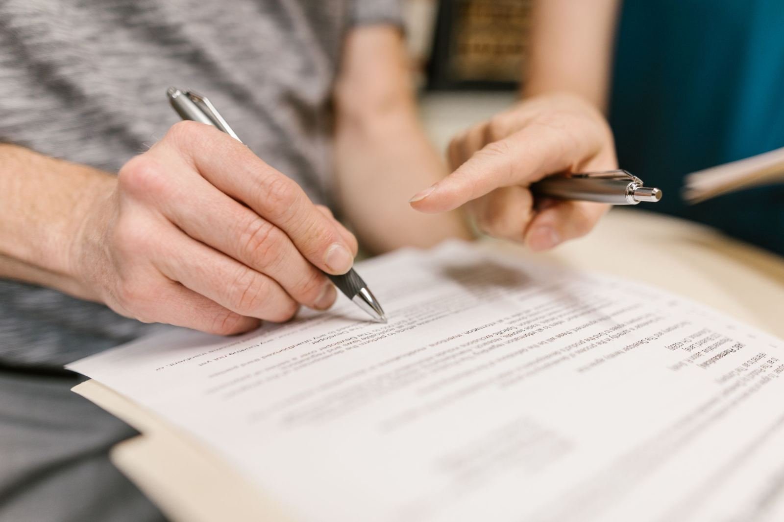 Two people review and sign paperwork at a desk