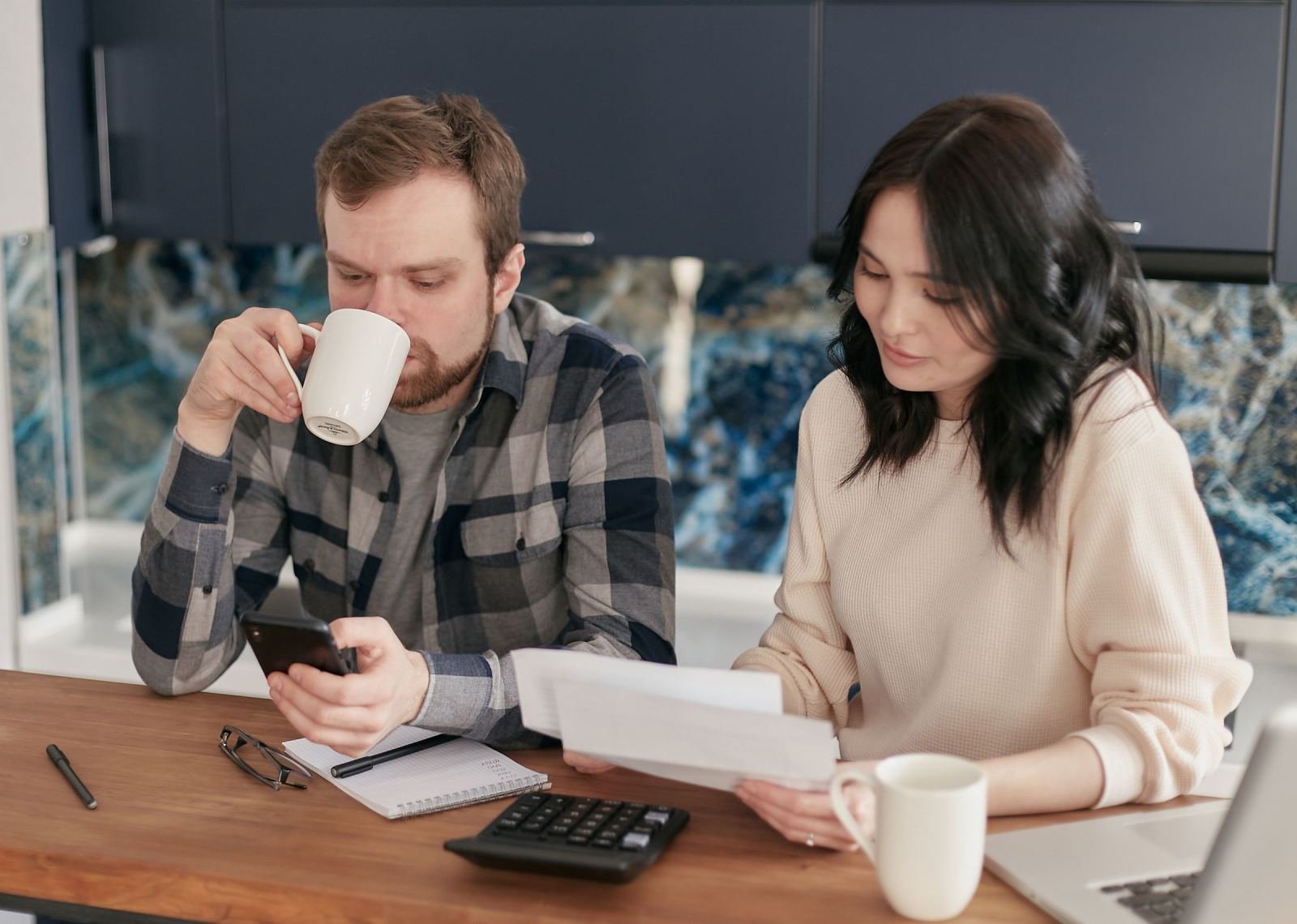 A man and woman review documents and use a calculator at a table