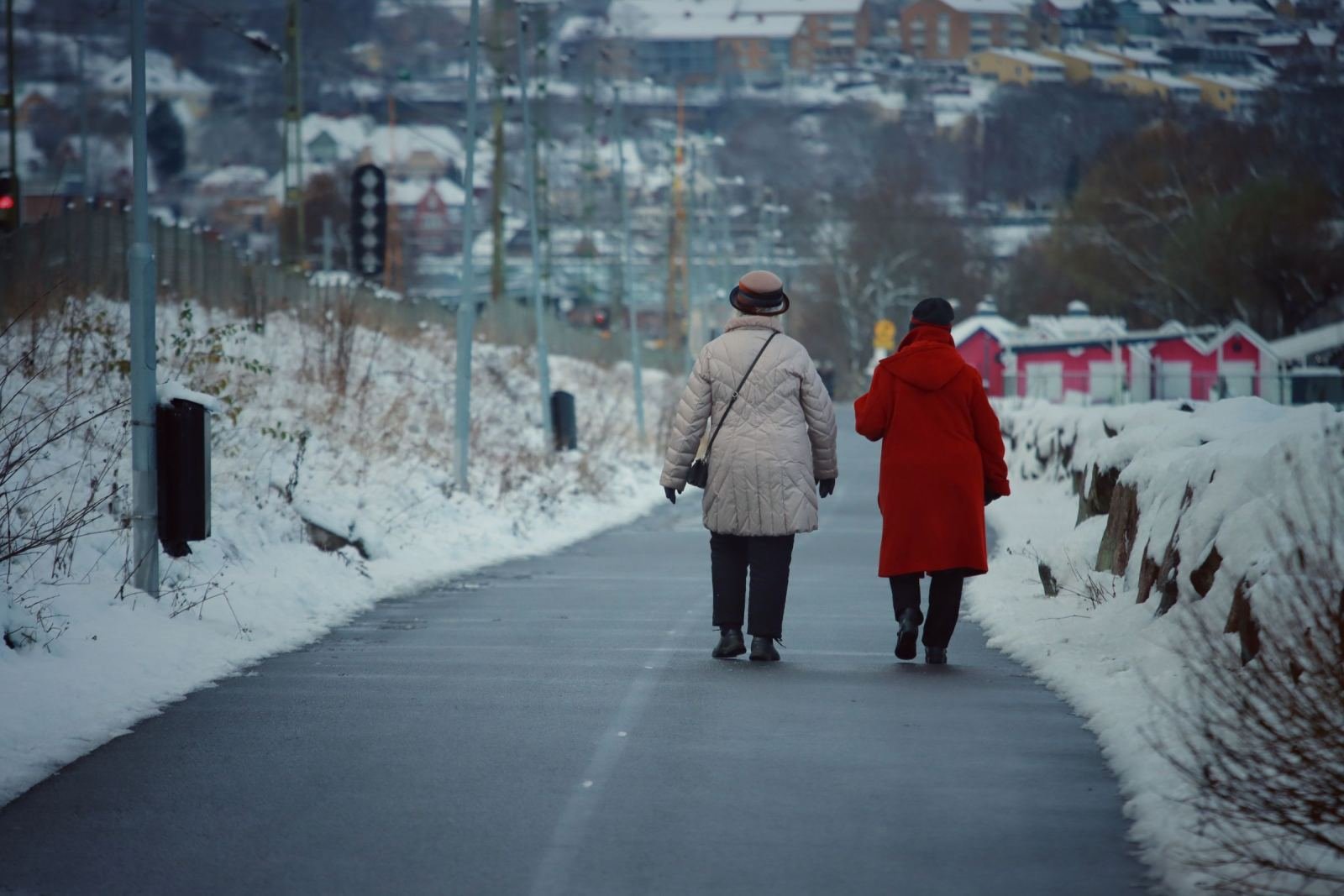 A snowy trail shows two people in winter coats moving away from the camera